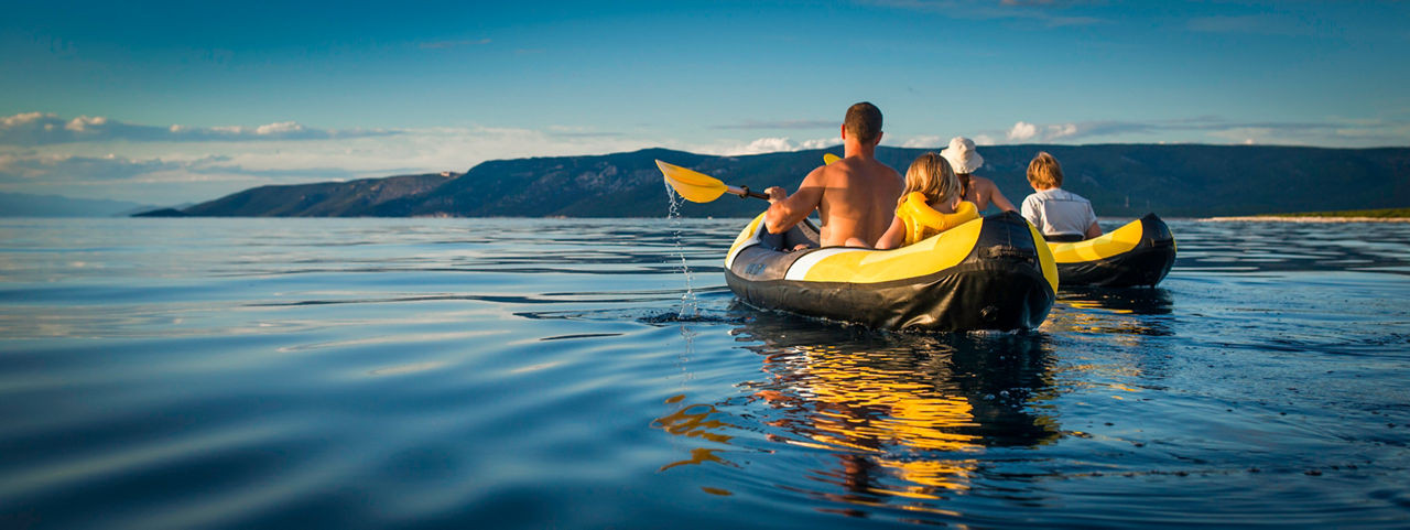 Panoramic shot of young family enjoy sea kayaking, rear view.